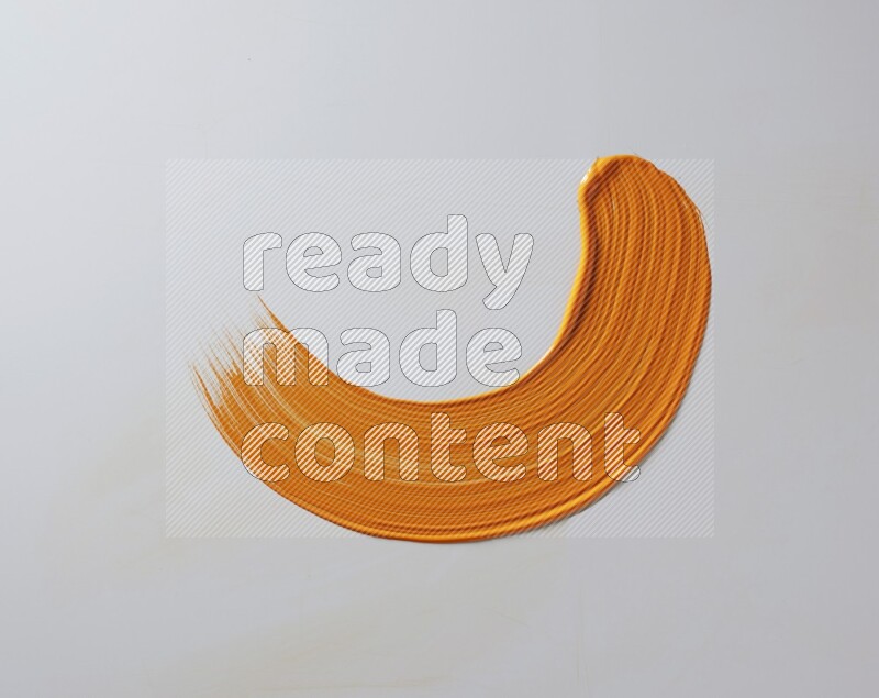 An orange half circular painting brush stroke on white background