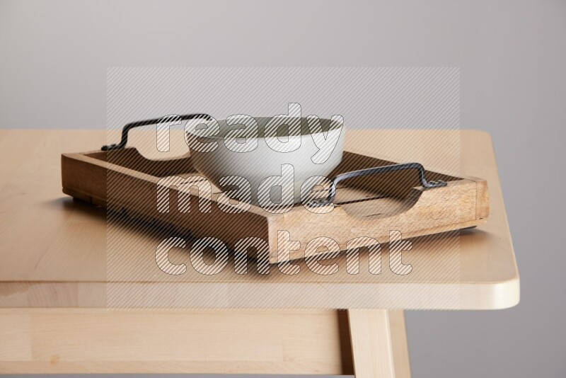 grey bowl on a light colored rectangular wooden tray with handles