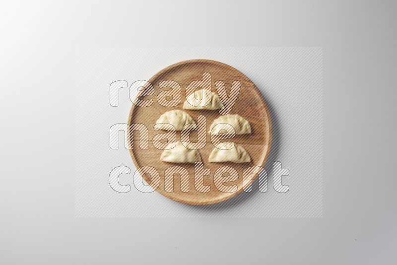Five Sambosas on a wooden round plate on a white background