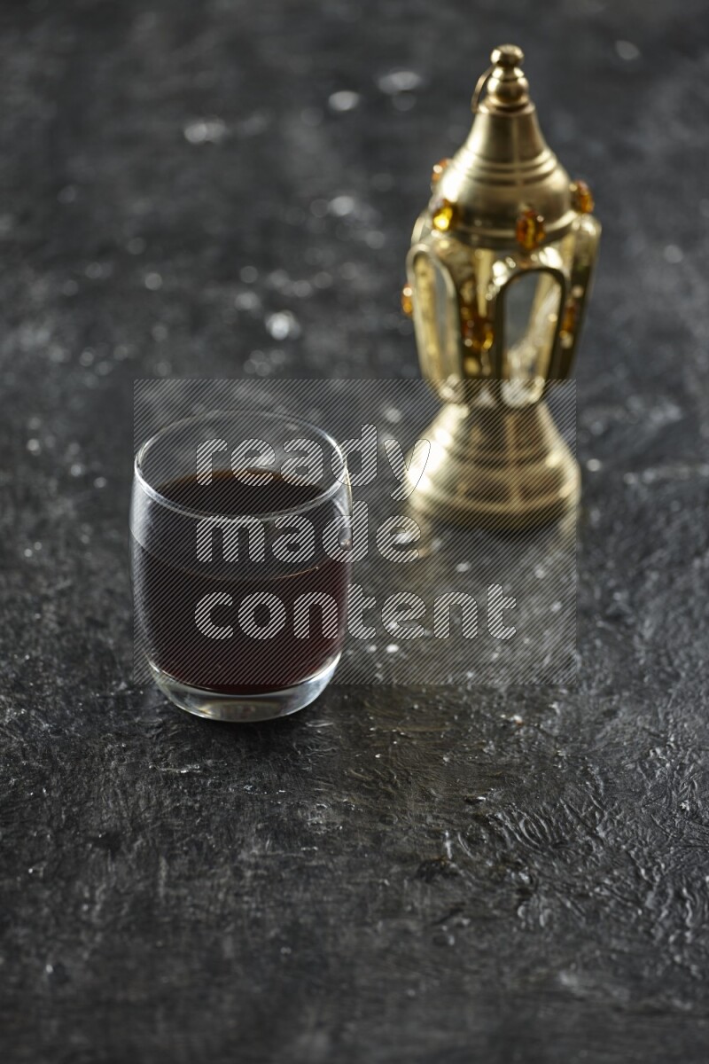 فانوس ذهبي مع مشروبات مختلفة وتمر ومكسرات وسبحة صلاة وقرآن على خلفية سوداء