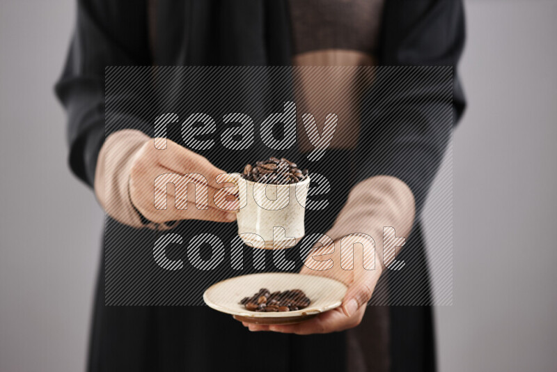 Woman in abaya holding different kinds of coffee beans in different positions