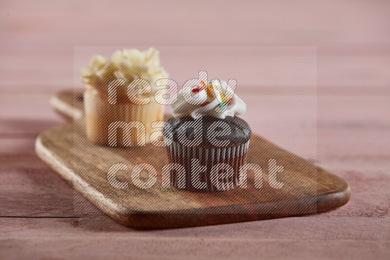Chocolate mini cupcake topped with cream on a wooden board