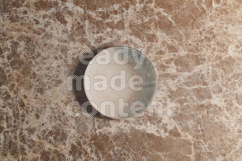 A multicolored pottery plate on beige marble background