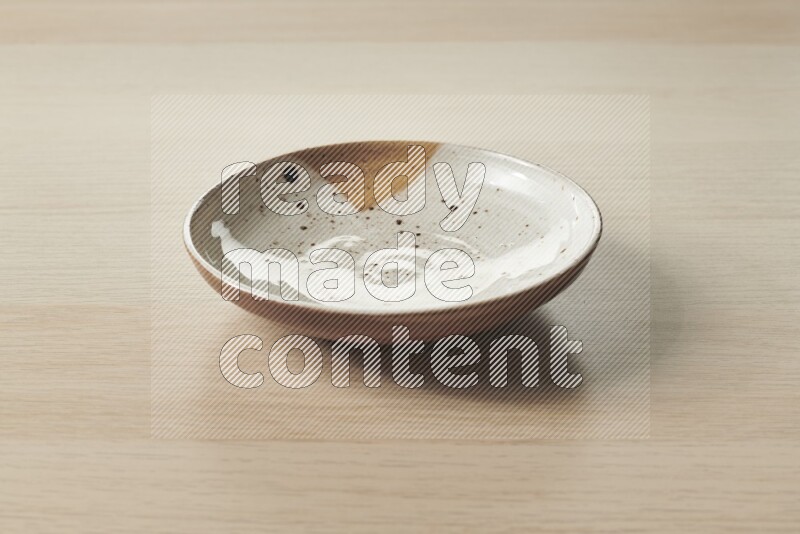 A multicolored pottery plate on light wooden background