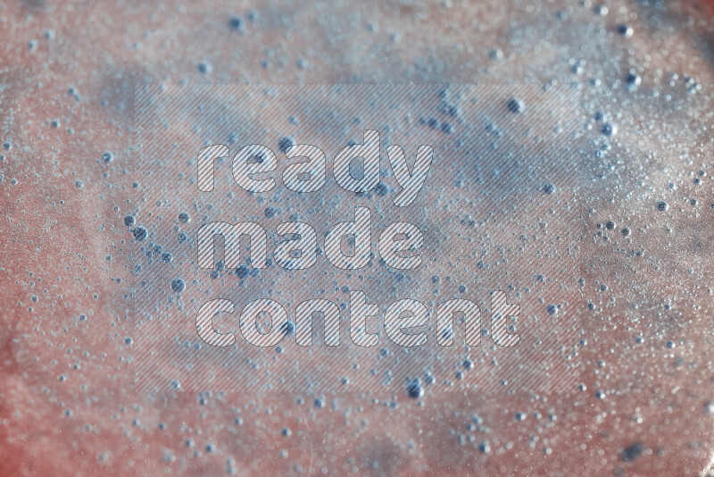 Close-ups of abstract blue watercolor drops on oil Surface on red background