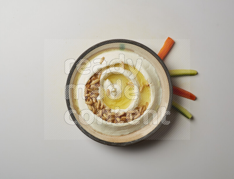 Lebnah garnished with pine nuts in a pottery plate on a white background