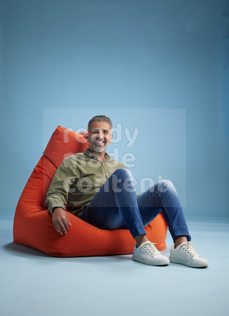 A man sitting on an orange beanbag and interacting with the camera
