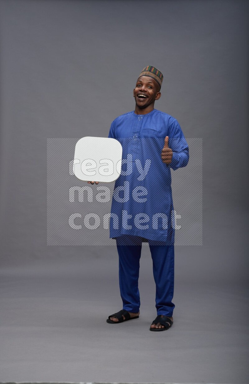 Man wearing Nigerian outfit standing holding social media sign on gray background