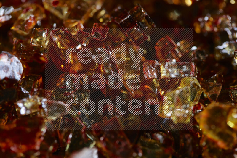Transparent orange fragments of glass scattered on a black background