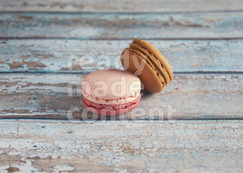 45º Shot of of two assorted Brown Irish Cream, and Pink Litchi Raspberry macarons on light blue background