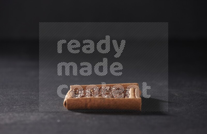 أربعة من أعواد القرفة مكونة شكل مربع بداخلها بذور الكتان علي خلفية سوداء