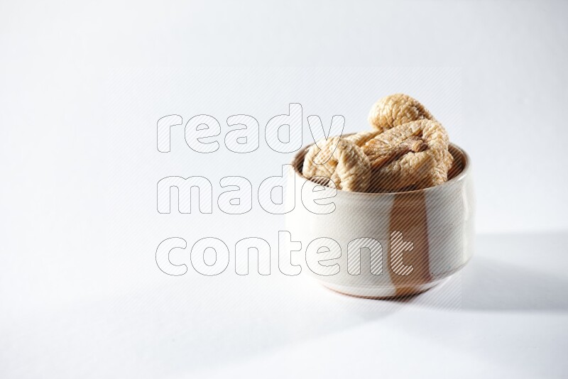A beige ceramic bowl full of dried figs on a white background in different angles
