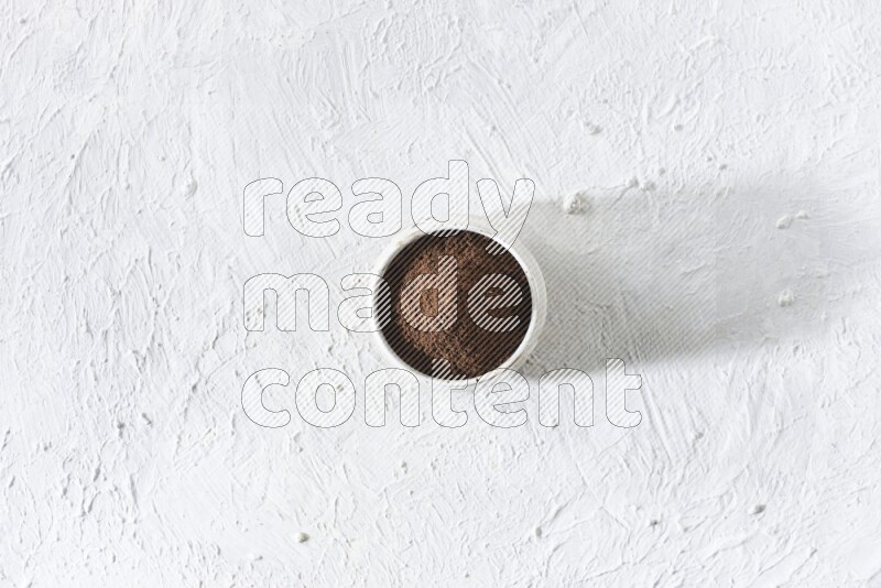 وعاء بيج من السيراميك ممتلئ ببودرة القرنفل علي خلفية بيضاء