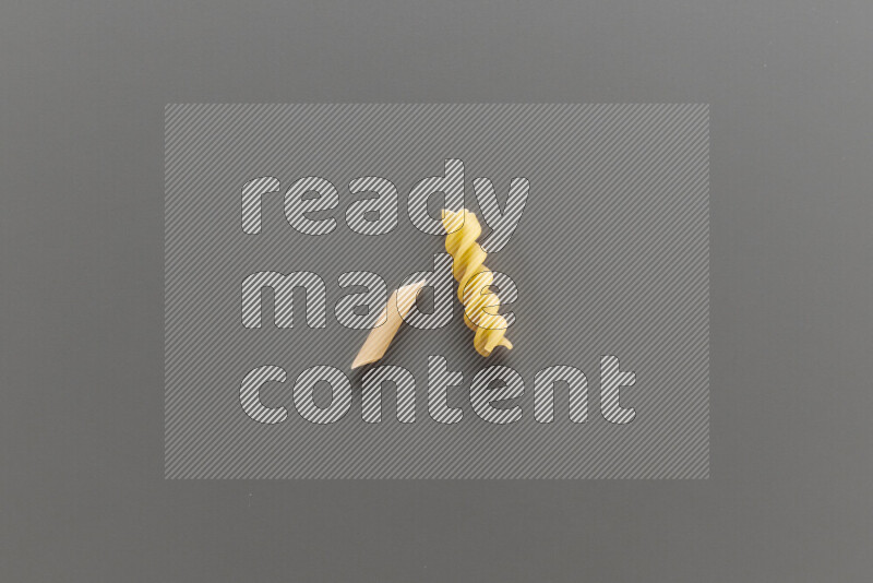 Mini penne pasta with other types of pasta on grey background