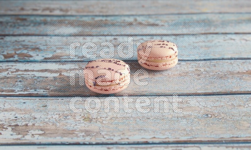 45º Shot of two pink orange blossom macarons on light blue wooden background