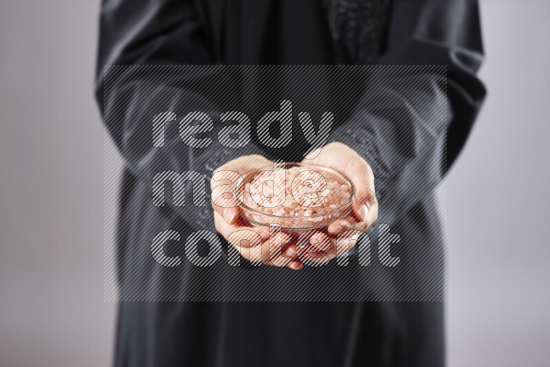 Woman in abaya holding different kinds of spices in different positions
