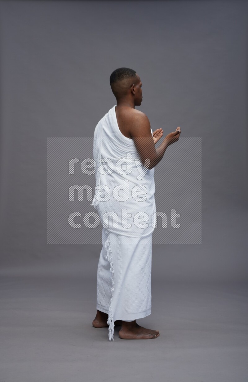 A man wearing Ehram Standing dua'a on gray background