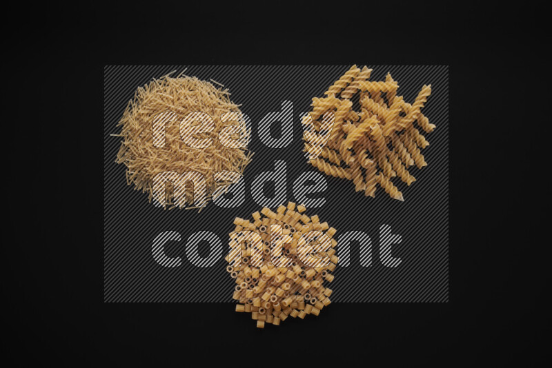 Different pasta types in bunches on black background