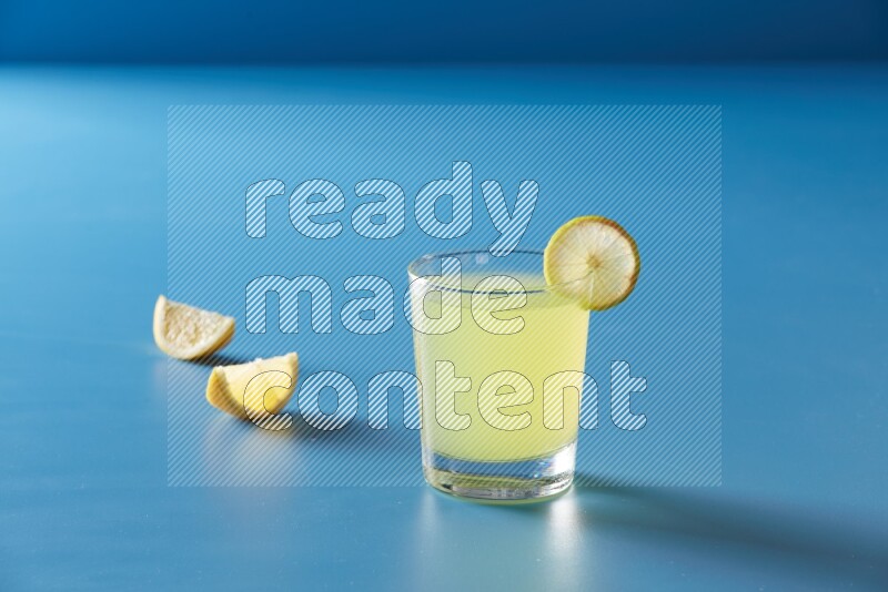 glass of lemon juice with lemon slice  on blue background