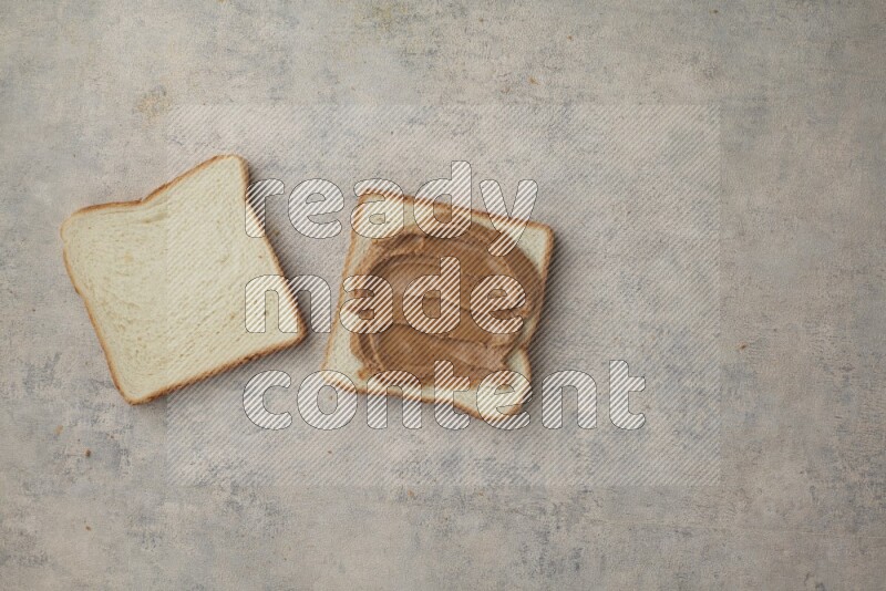 Creamy peanut butter on white toast and white toast slices on a light blue textured background