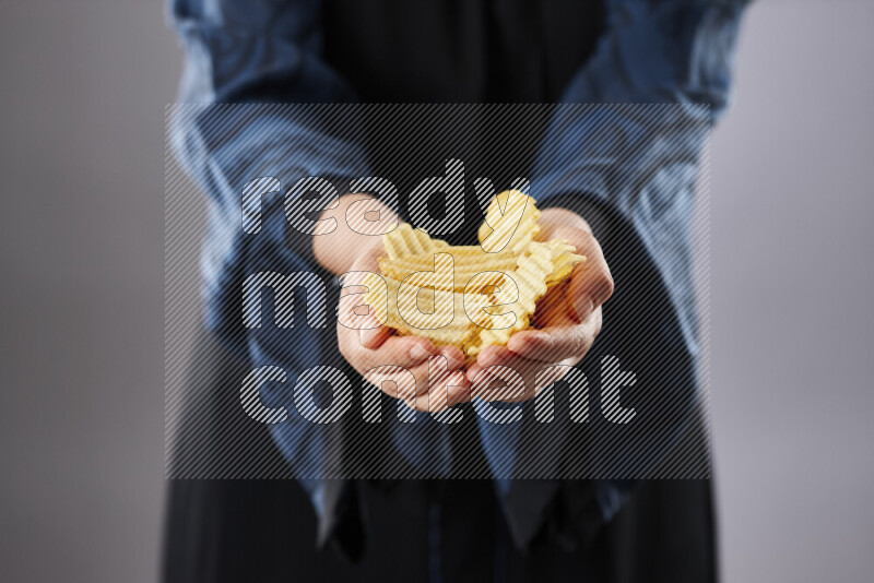 Woman in abaya holding different kinds of snacks in different positions