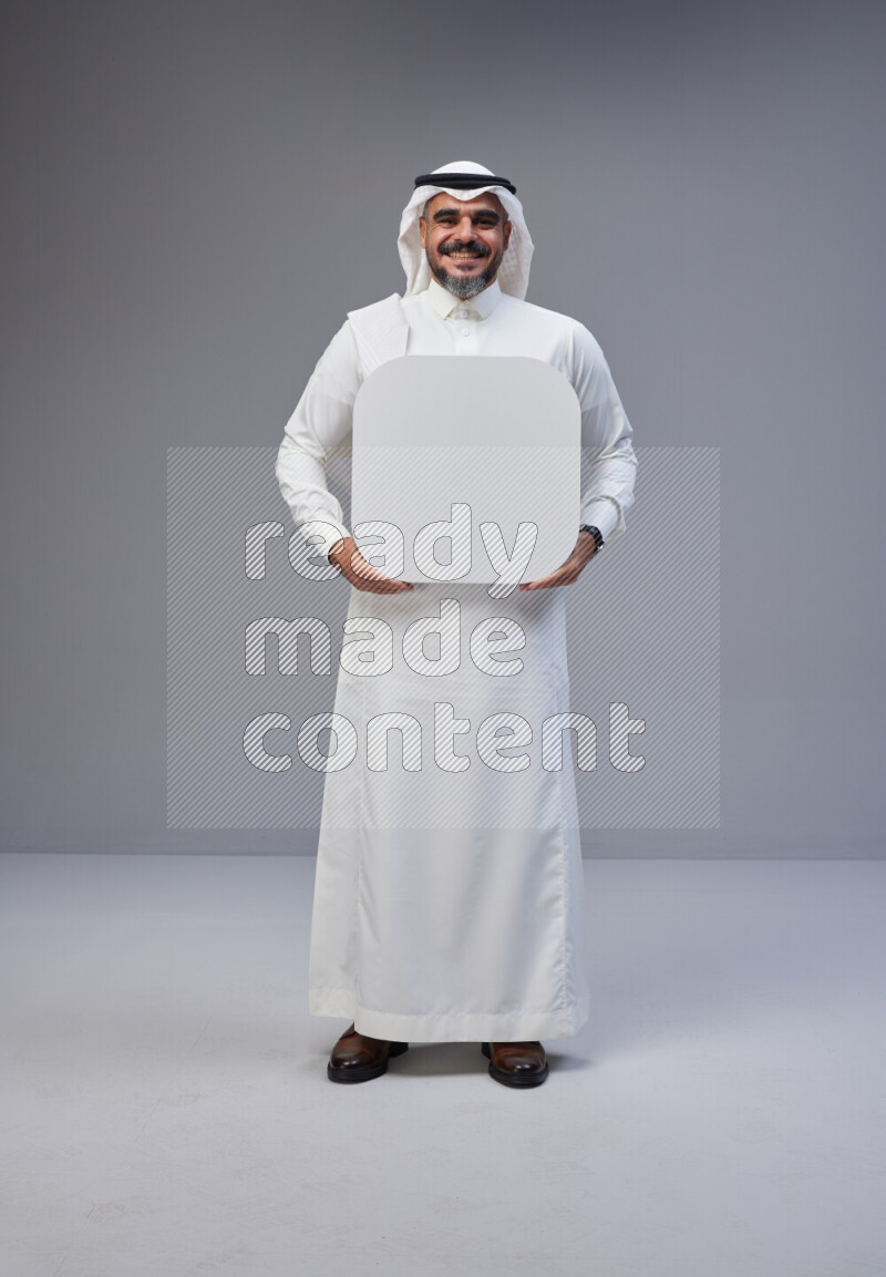 Saudi man Wearing Thob and white Shomag standing holding social media sign on Gray background