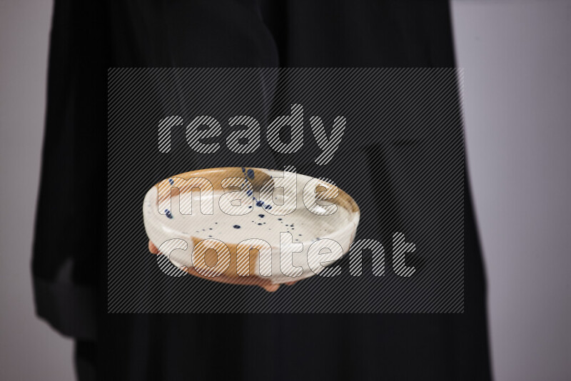 A woman in black abaya holding different pottery essentials in different positions