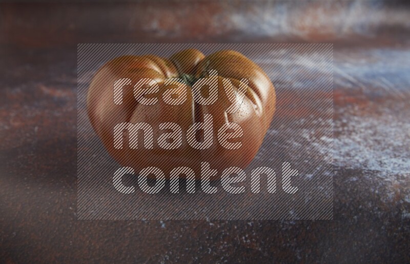 45 degree single heirloom tomato on  a textured reddish rustic metal background