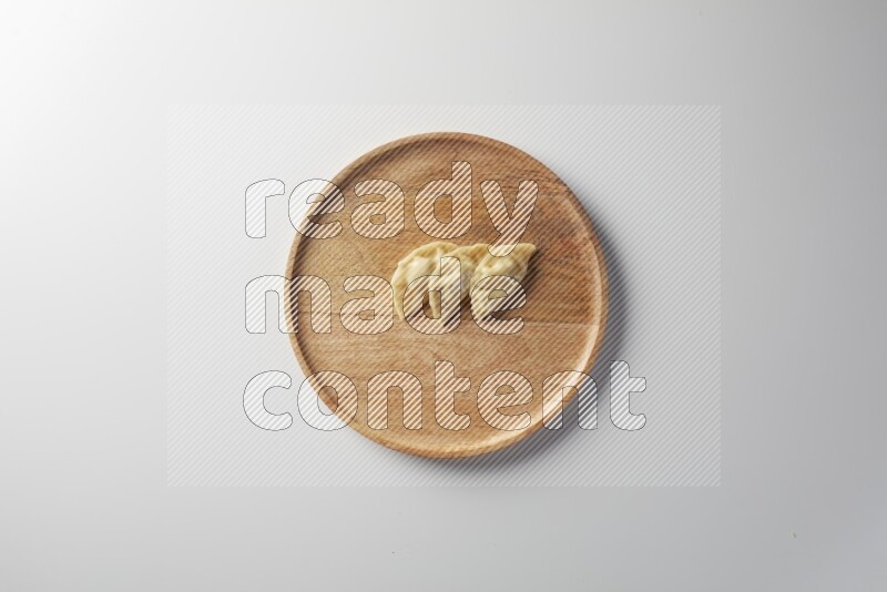 Three Sambosas on a wooden round plate on a white background