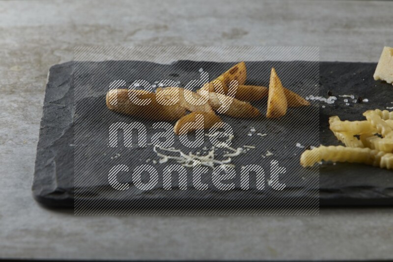 Mixed potatoes with cheese on a black stone serving platter on grey textured counter top