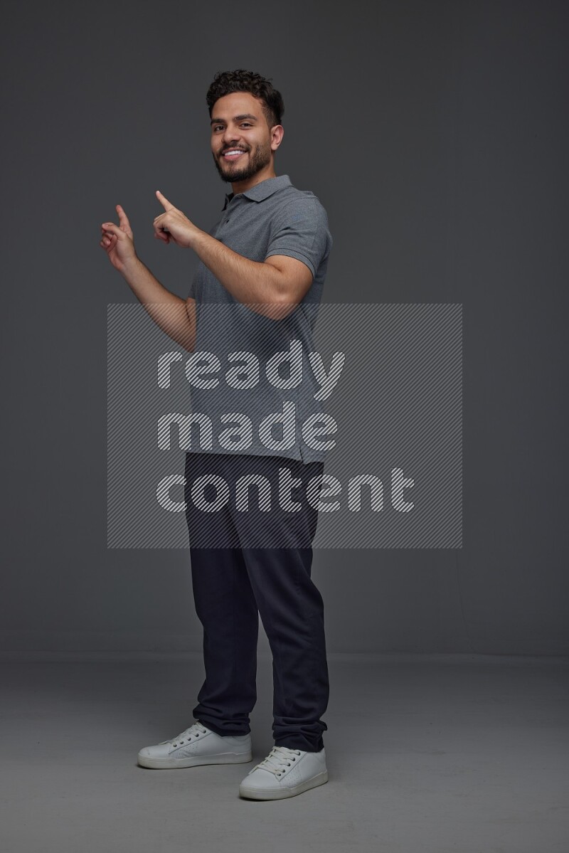 A man wearing casual standing and making multi hand gestures eye level on a gray background
