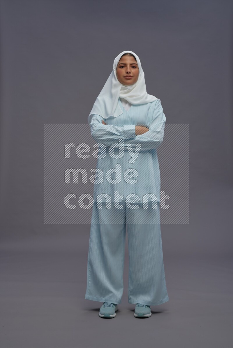 Saudi woman wearing hijab clothes standing with crossed arms on gray background