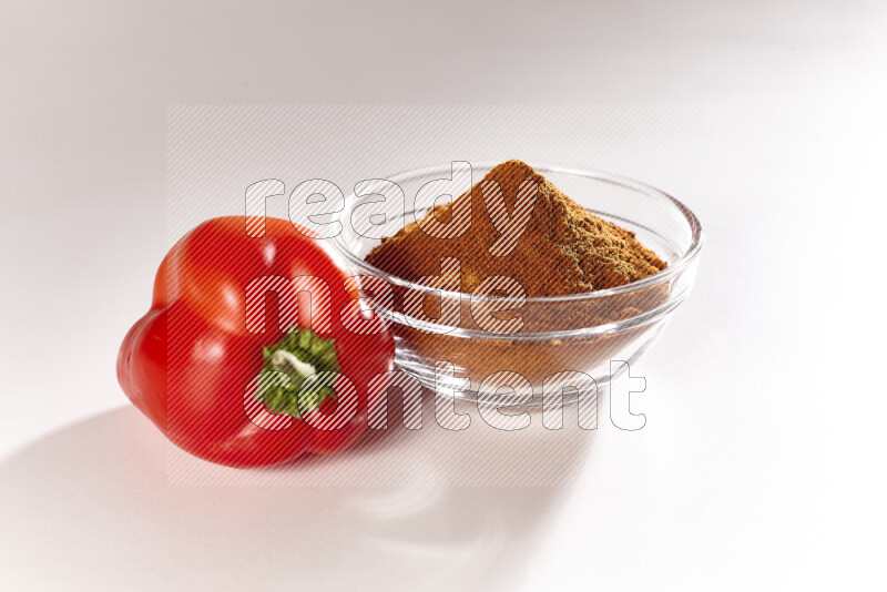 A glass bowl full of ground paprika powder on white background