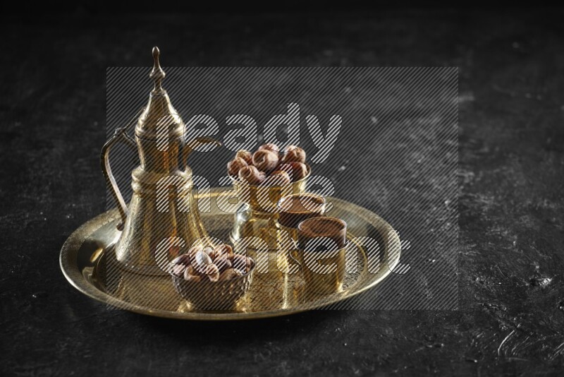 Nuts with dates and a drink on a metal tray in a dark setup