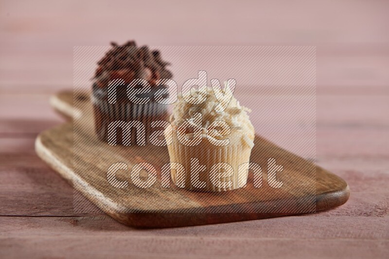 Vanilla mini cupcake topped with coconut on a wooden board