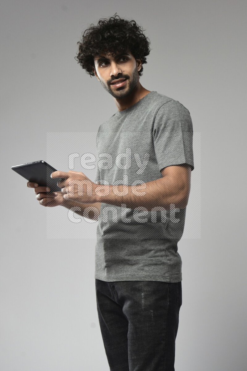 A man wearing casual standing and gaming on a tablet on white background