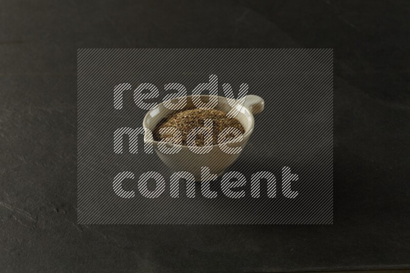 multi color round sauce bowl filled with herbs on grey textured countertop