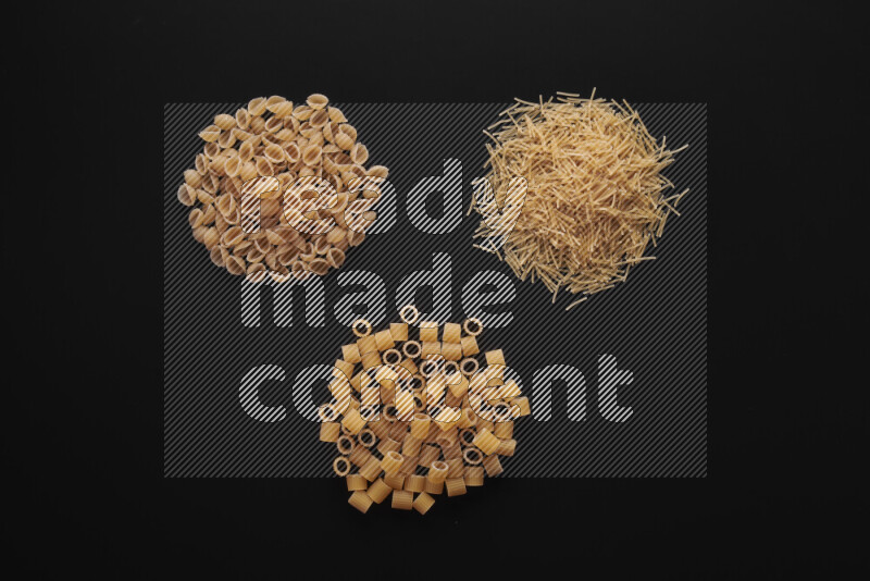 Different pasta types in bunches on black background