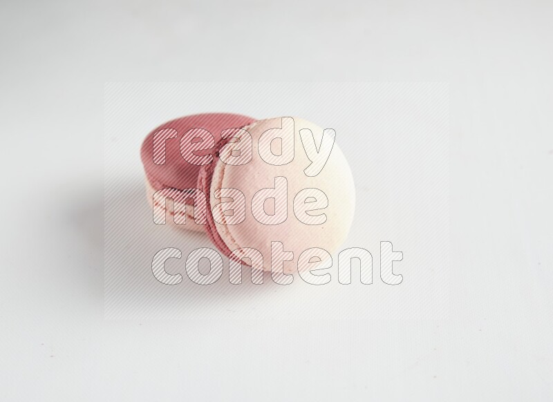 45º Shot of two Pink Litchi Raspberry macarons on white background