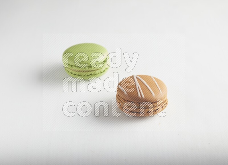 45º Shot of of two assorted Brown Irish Cream, and Green Pistachio macarons on white background