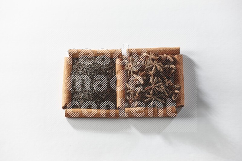 مربعان من أعواد القرفة ممتلئان باليانسون النجمي والشاي الأسود علي خلفية بيضاء