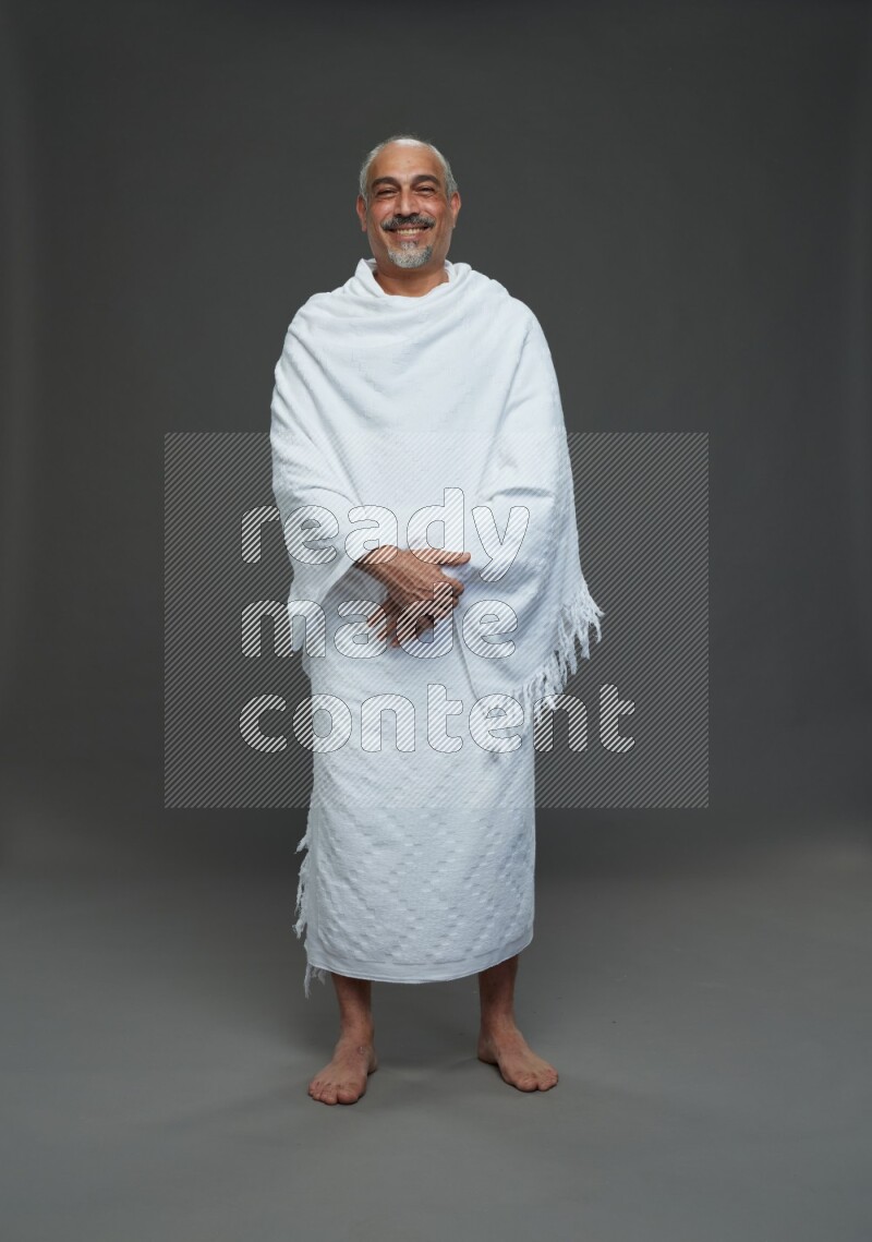 A man wearing Ehram Standing Interacting with the camera on gray background