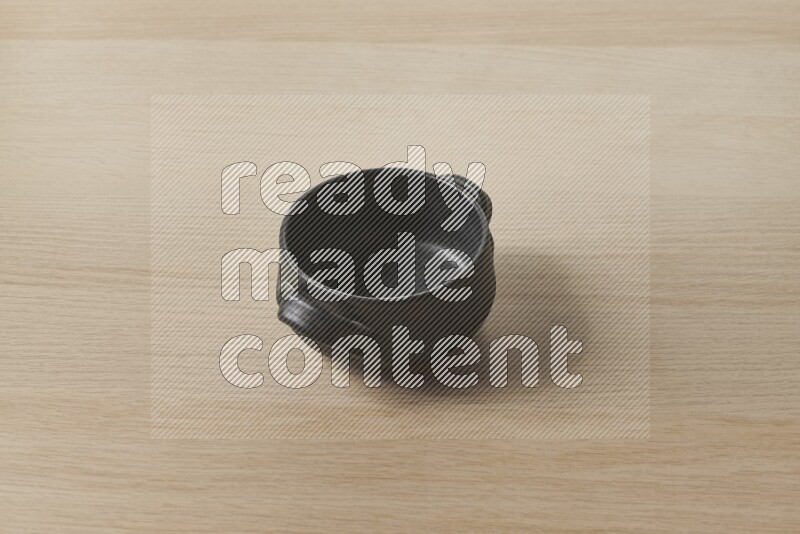 A black pottery bowl on light wooden background