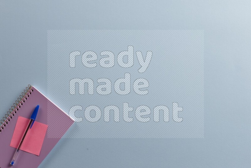 A purple notebook with different school supplies on blue background