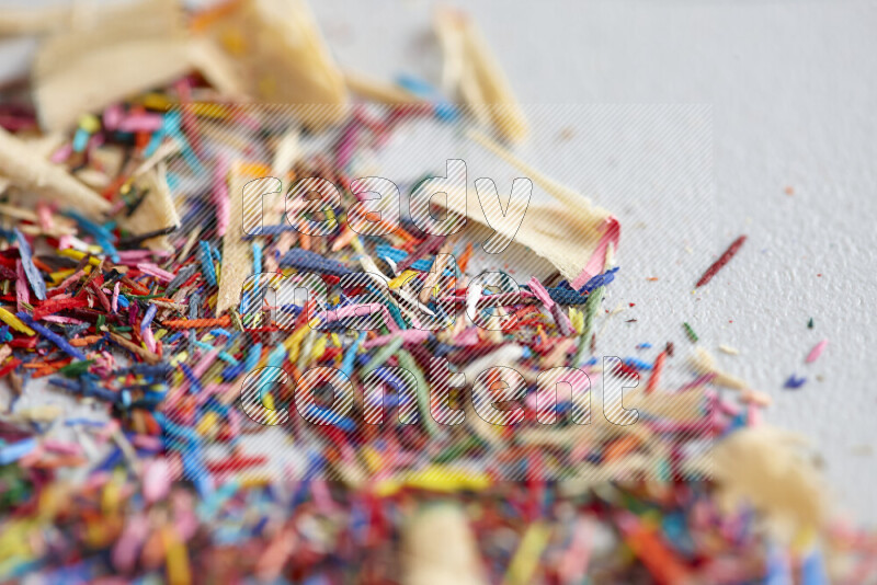 This image showcases a vibrant multicolored pencil shavings scattered on grey background