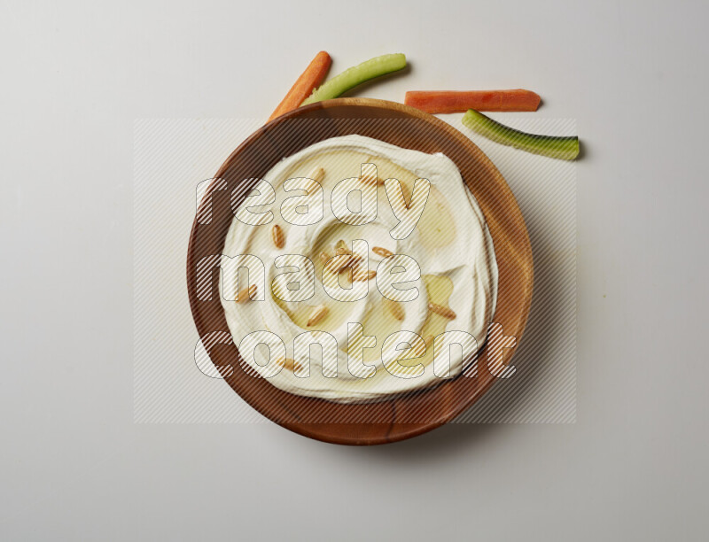 Lebnah garnished with pine nuts in a wooden plate on a white background