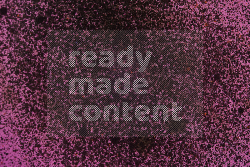 Close-ups of abstract black watercolor drops on oil Surface on pink background