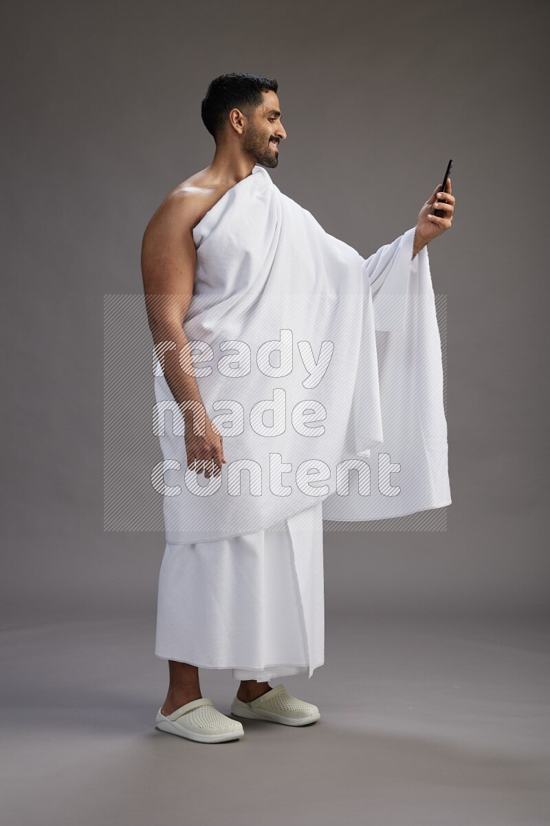 A man wearing Ehram Standing taking selfie on gray background