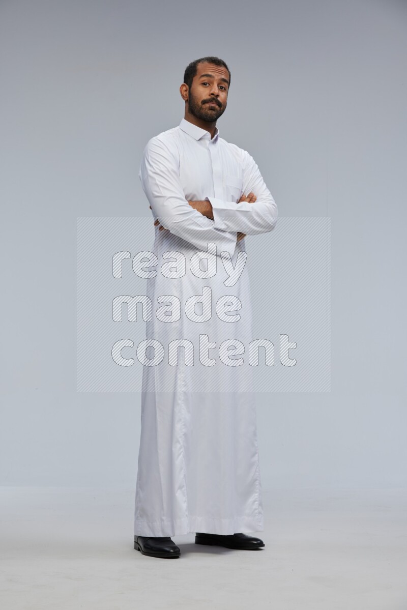 Saudi man wearing Thob standing with crossed arms on Gray background