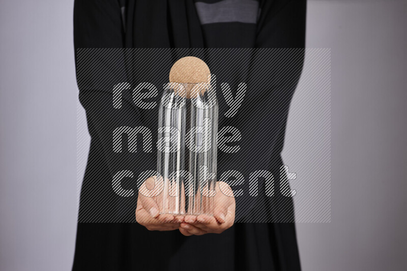 A woman in black abaya holding different glassware in different positions